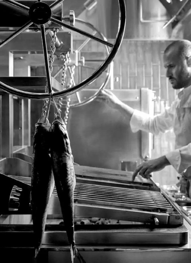 Koch bedient das Handrad des Hebemechanismus am KOPA Parilla-Grill